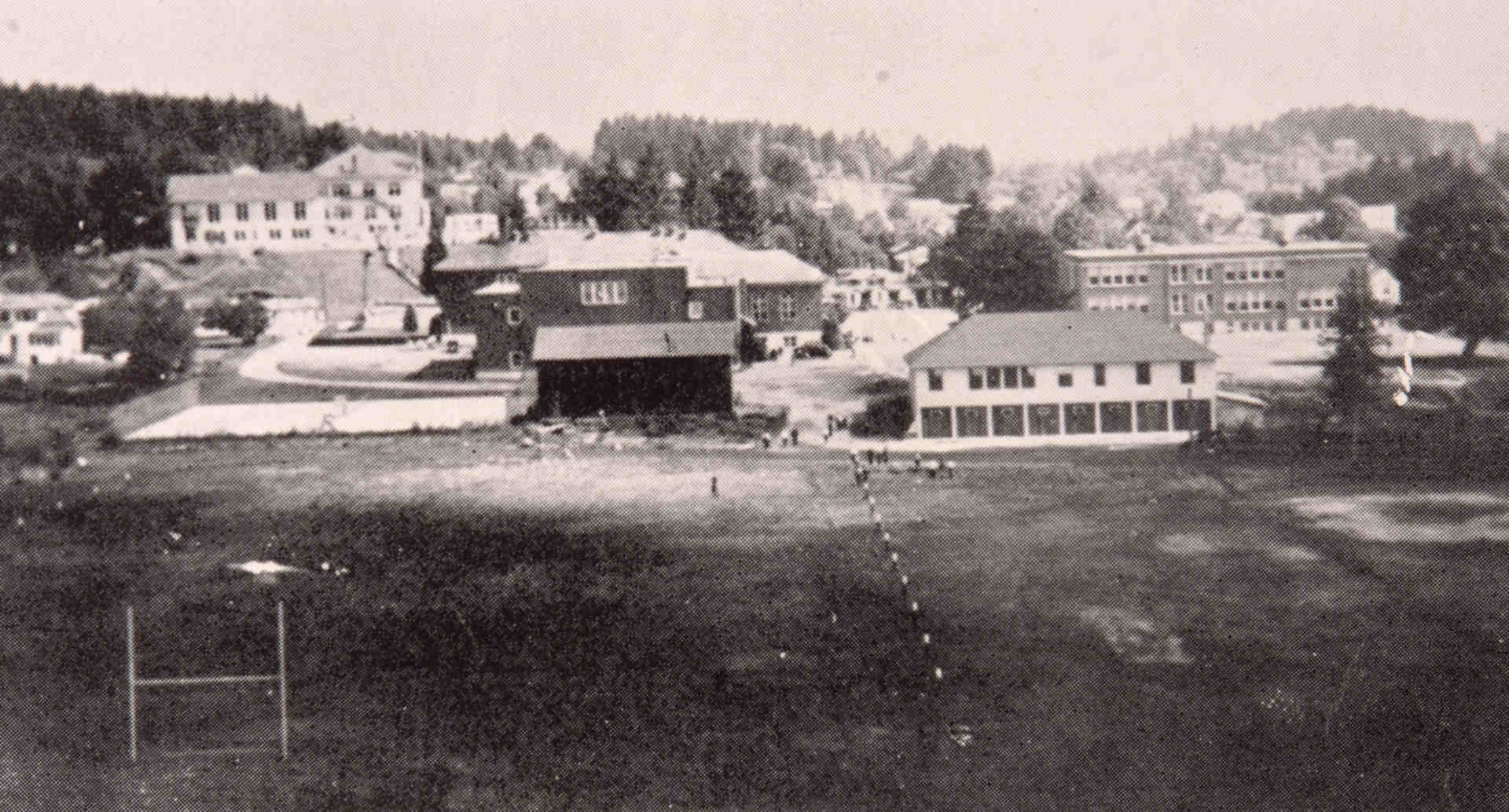 view from football field looking at high school on left, junior high school on right, and white school on the hill